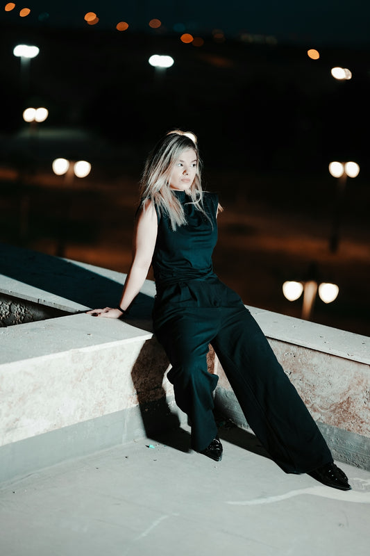 A woman in a black dress sitting on a ledge
