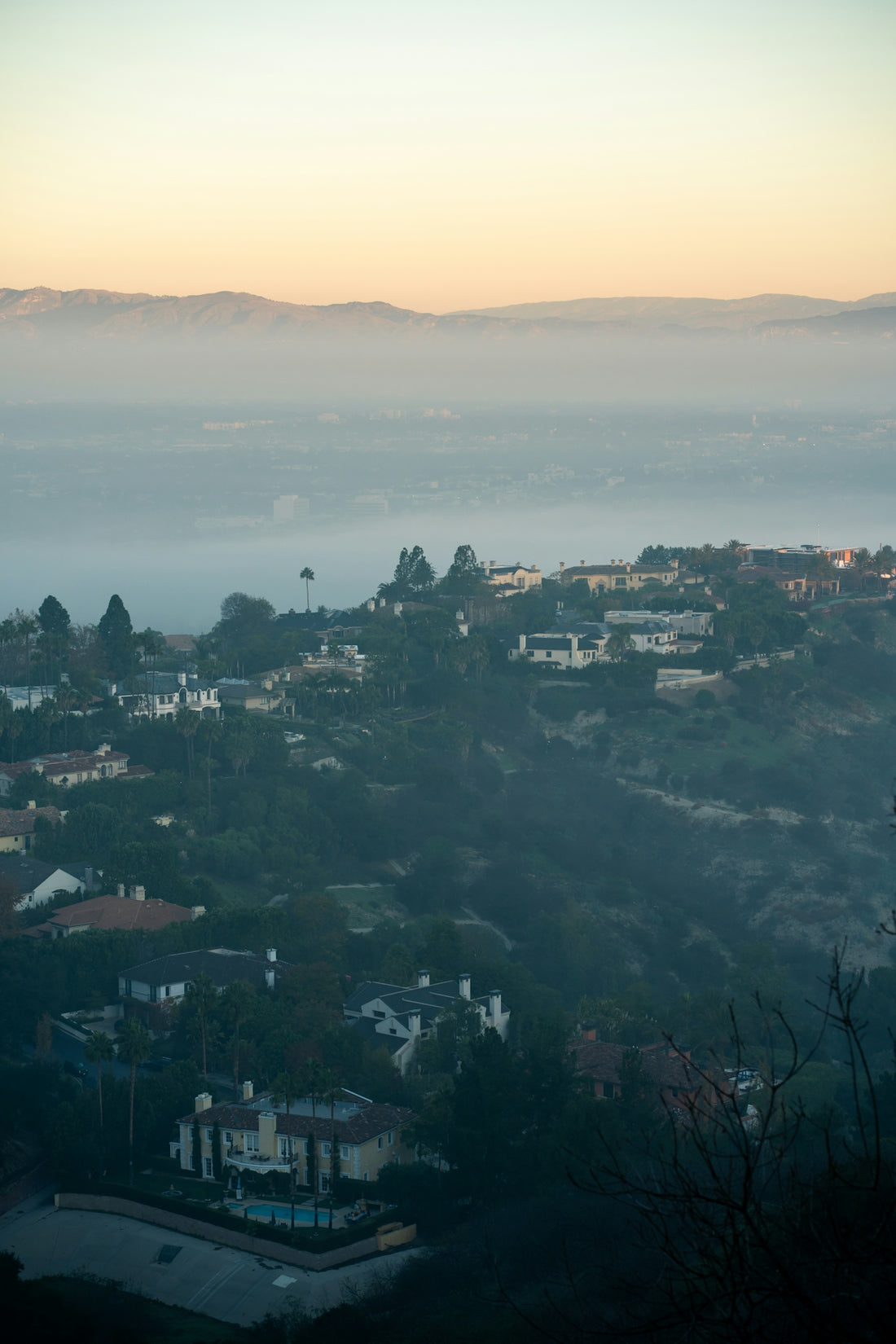 Suburban neighborhood nestled in misty hills at dawn.