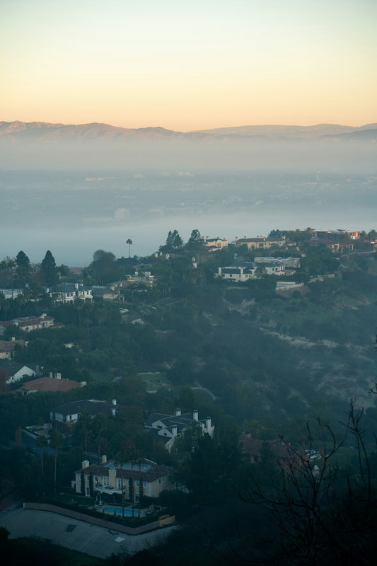 Suburban neighborhood nestled in misty hills at dawn.
